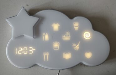De Fisher-Price Lumalou aan de muur, met de klok en de routine-iconen aan